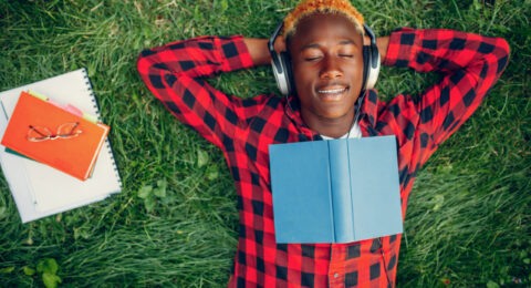 Black student resting on the grass, top view