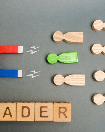 Magnet, crowd of workers and the word Leader on wooden blocks. Concept of choosing a new leader from the team. Leadership. Talented successful employee.