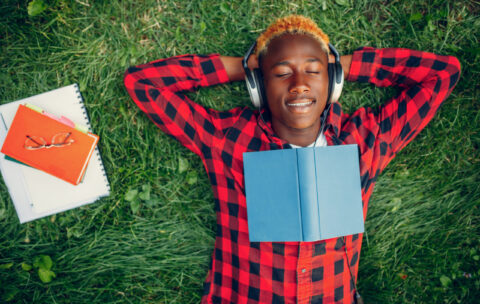 Black student resting on the grass, top view