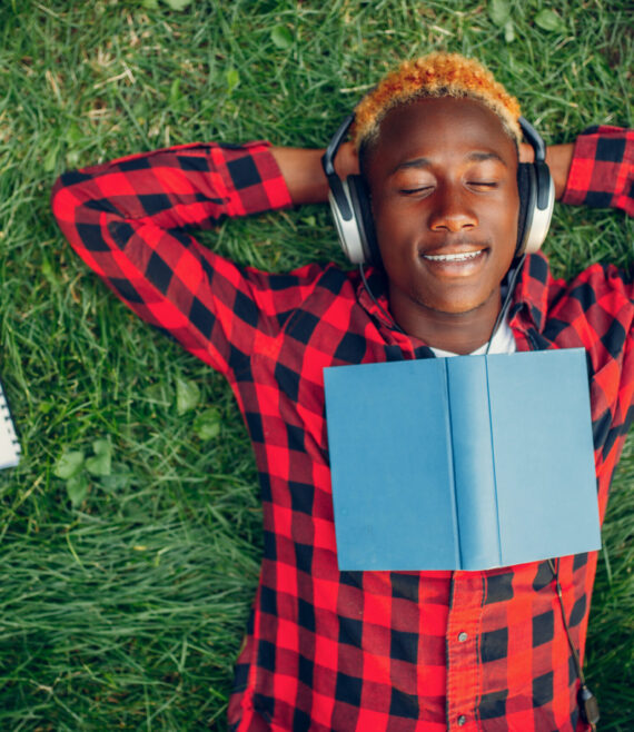 Black student resting on the grass, top view