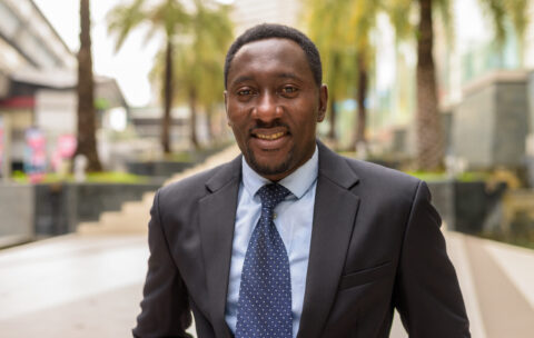 Portrait of handsome African businessman in city smiling